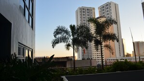 A modern building with large windows and a flat roof, surrounded by greenery and palm trees. - Eton Parkview (Makati)