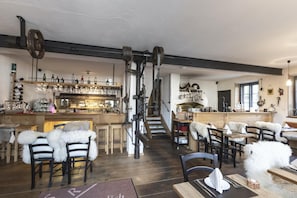 A rustic interior with wooden furniture, a bar area, and a staircase. - Hotel Oberschmied (Reit im Winkl)