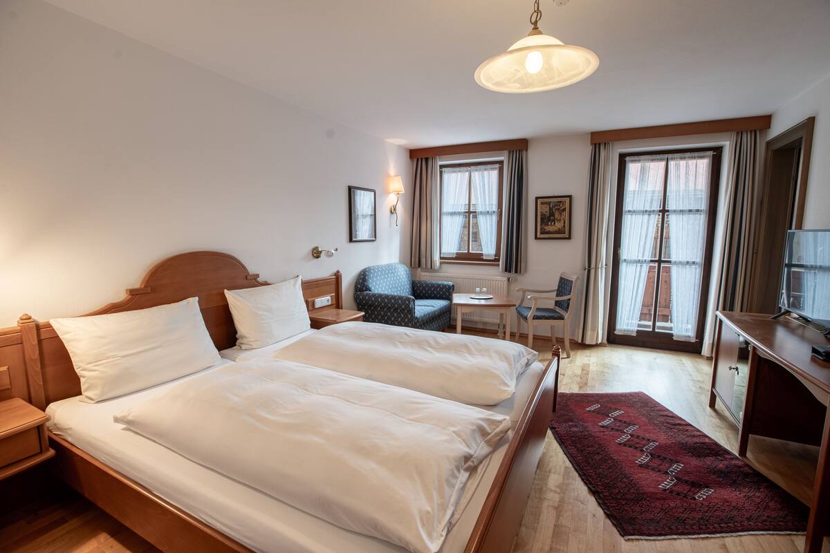 Ett hotellrum med en stor säng, sängbord, ett skrivbord, en stol och en TV.