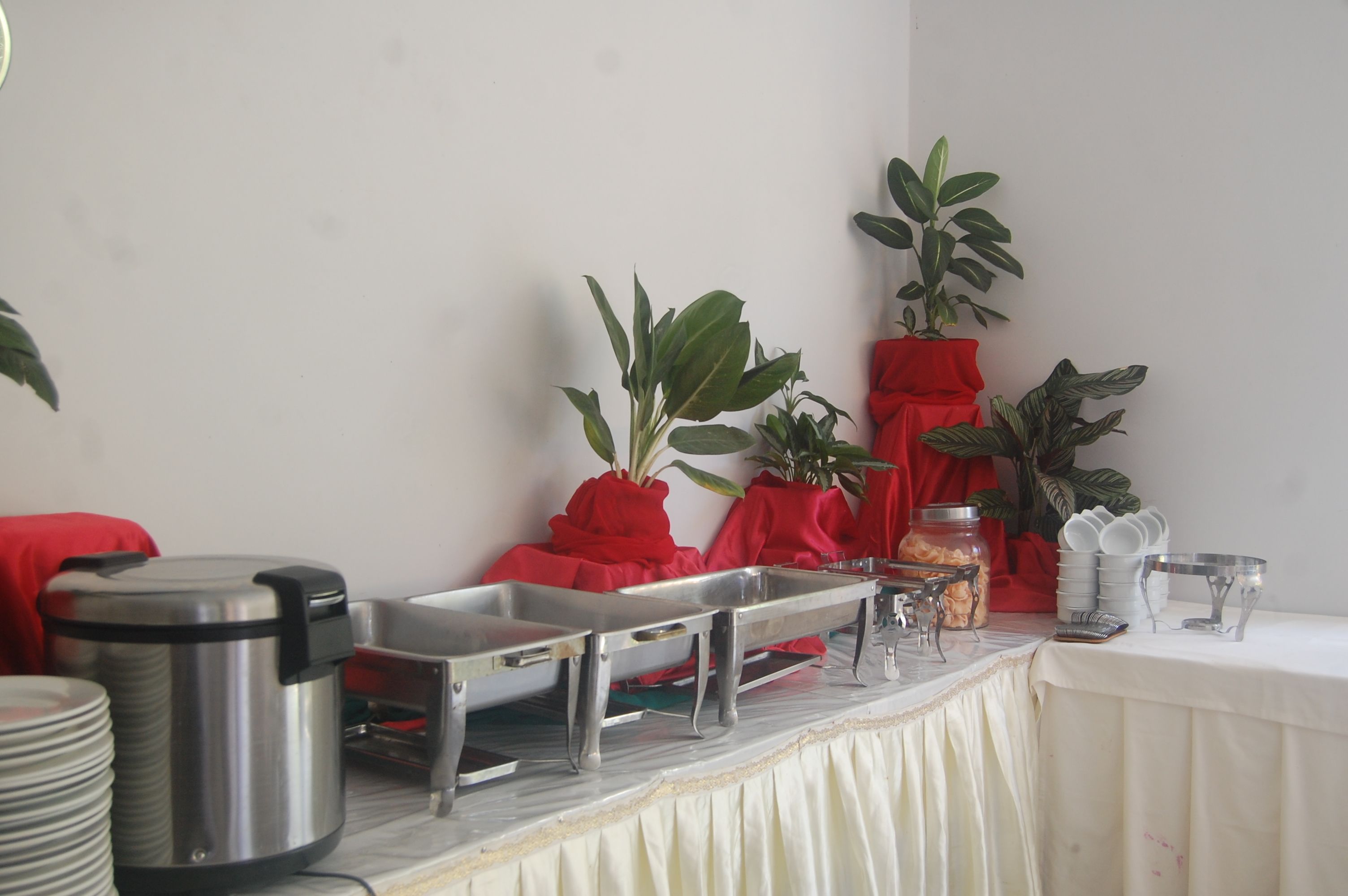 A buffet setup with stainless steel serving trays, a coffee pot, and a jar of snacks.