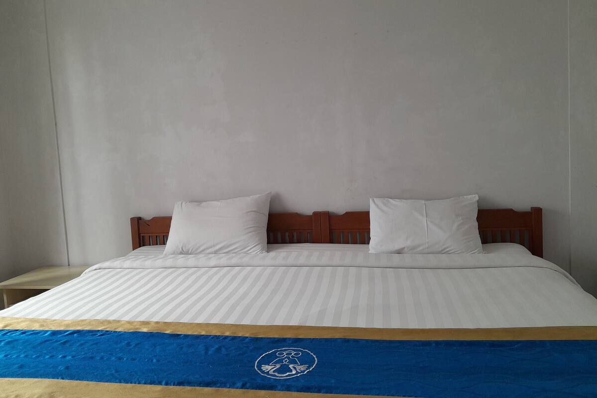 A bed with a blue and gold bedspread, two white pillows, and a wooden headboard.
