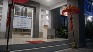 A hotel entrance with a reception desk, a red carpet, and two red umbrellas. - Dhyanapura City Hotel (Mengwi)