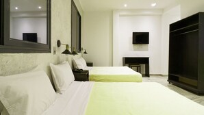 A hotel room with two beds, a large mirror, a flat-screen TV, and a fireplace. - Hotel Roma Tunis (Tunis)