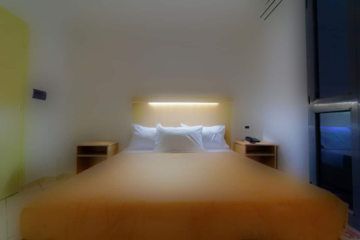 A hotel room with a bed, bedside tables, a nightstand, and a window with a view.