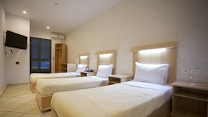 A hotel room with three single beds, a TV mounted on the wall, and a wooden wardrobe. - Hotel Roma Tunis (Tunis)