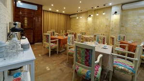 A dining area with multiple tables and chairs, a buffet setup, and a brick wall. - Hotel Roma Tunis (Tunis)