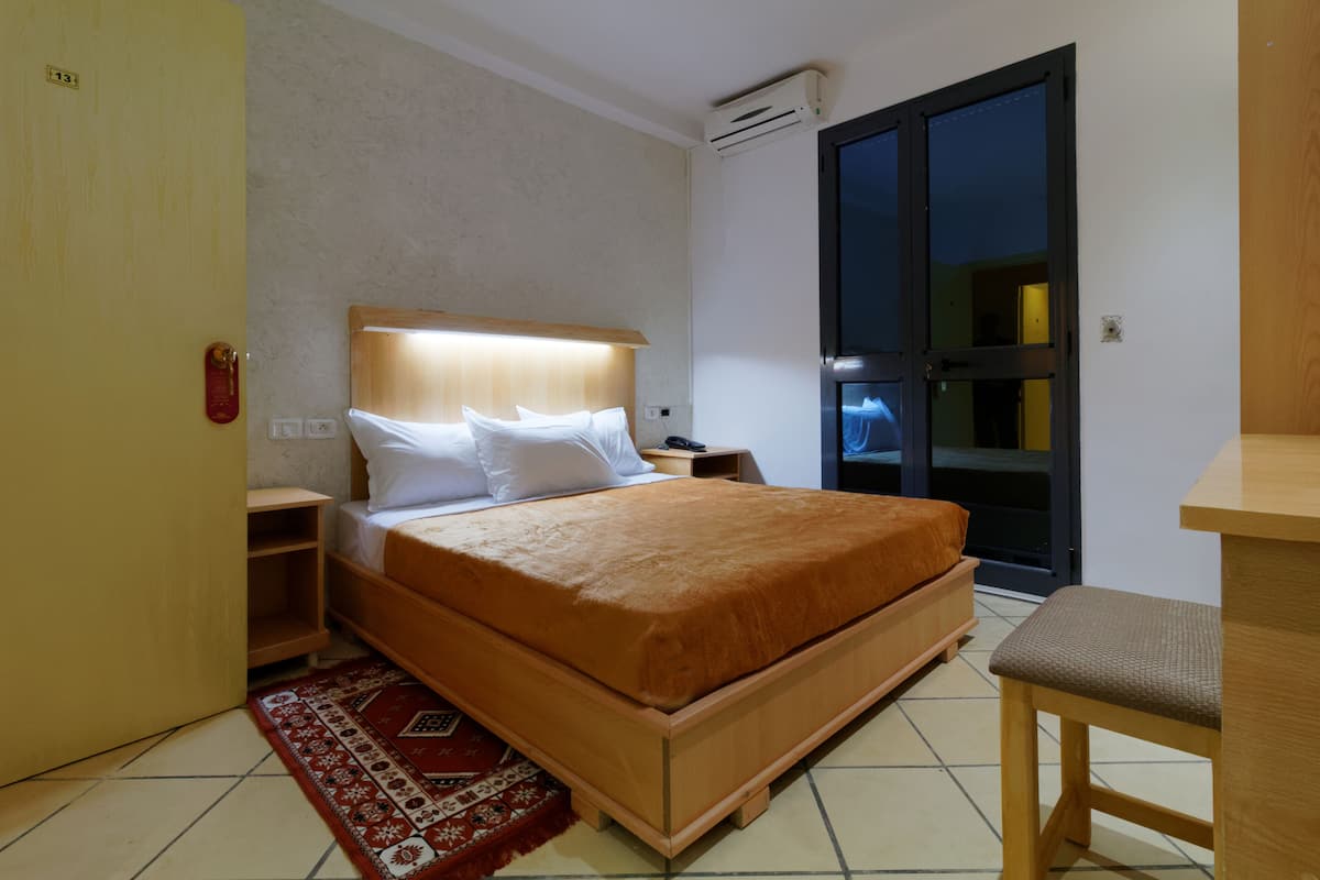 A neatly arranged bedroom with a bed, bedside table, and a small desk.