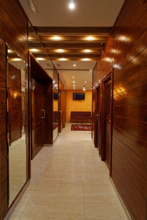 A hallway with wooden paneling, a bench, and a television mounted on the wall.