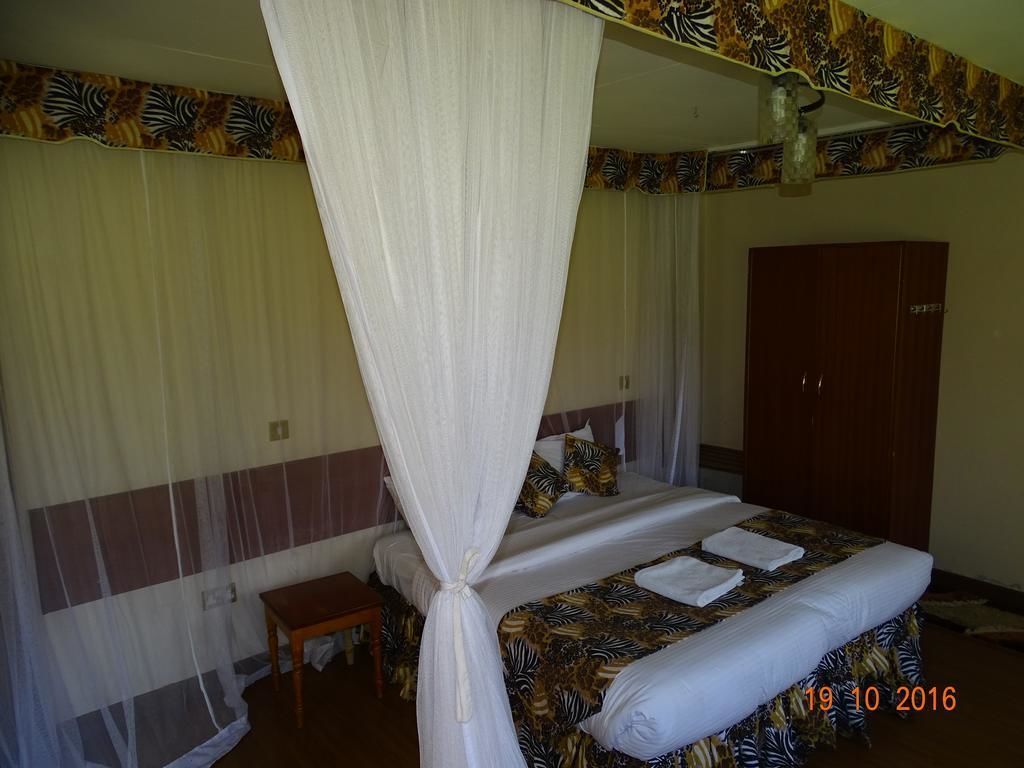 A room with a bed, a wooden nightstand, a wardrobe, and a mosquito net.