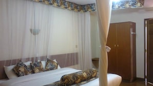 Quarto com cama, cortinas, guarda-roupa e dossel.