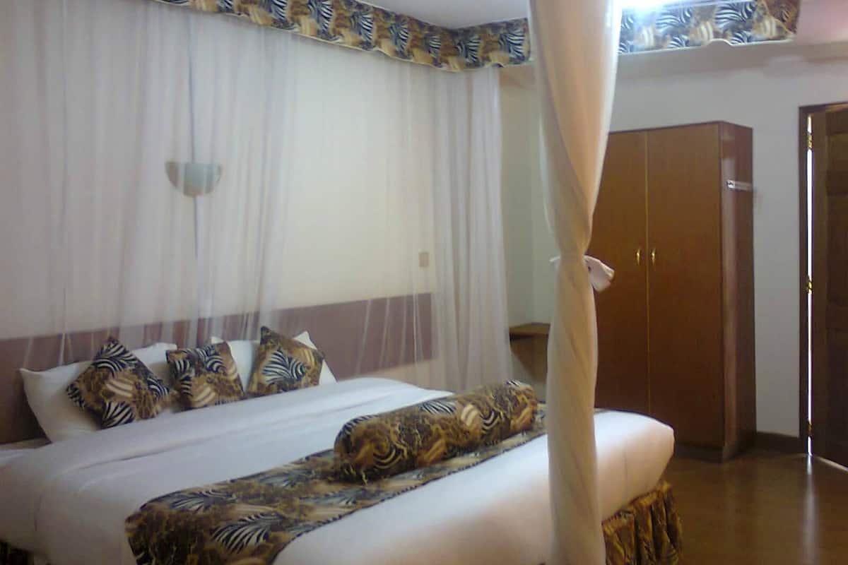 A bedroom with a bed, curtains, a wardrobe, and a canopy bed.