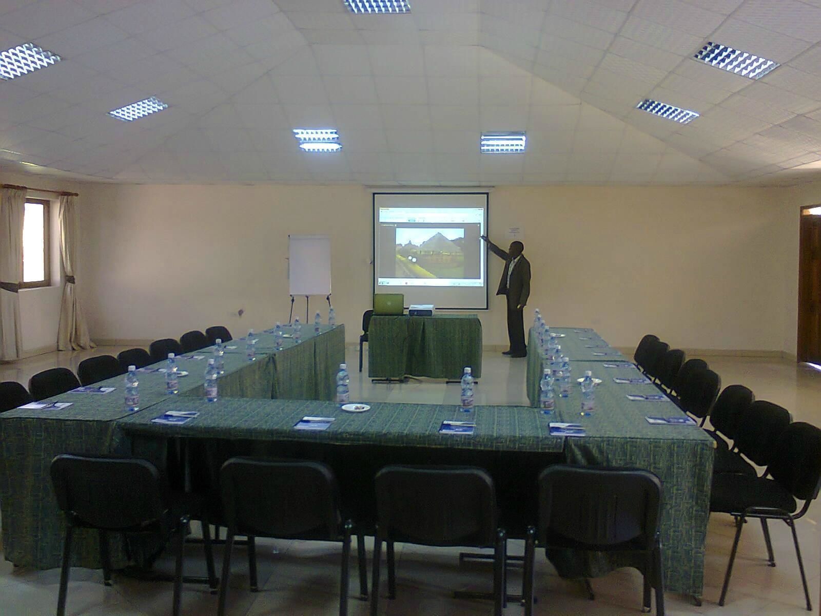 A conference room with a long table, chairs, a projector screen, and a presentation.