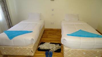Una habitación con dos camas, un tapete pequeño y un par de pantuflas en el suelo.