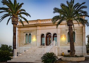 A building with a grand entrance, a staircase, and palm trees. - Tenuta Lama Gorga (Trani)