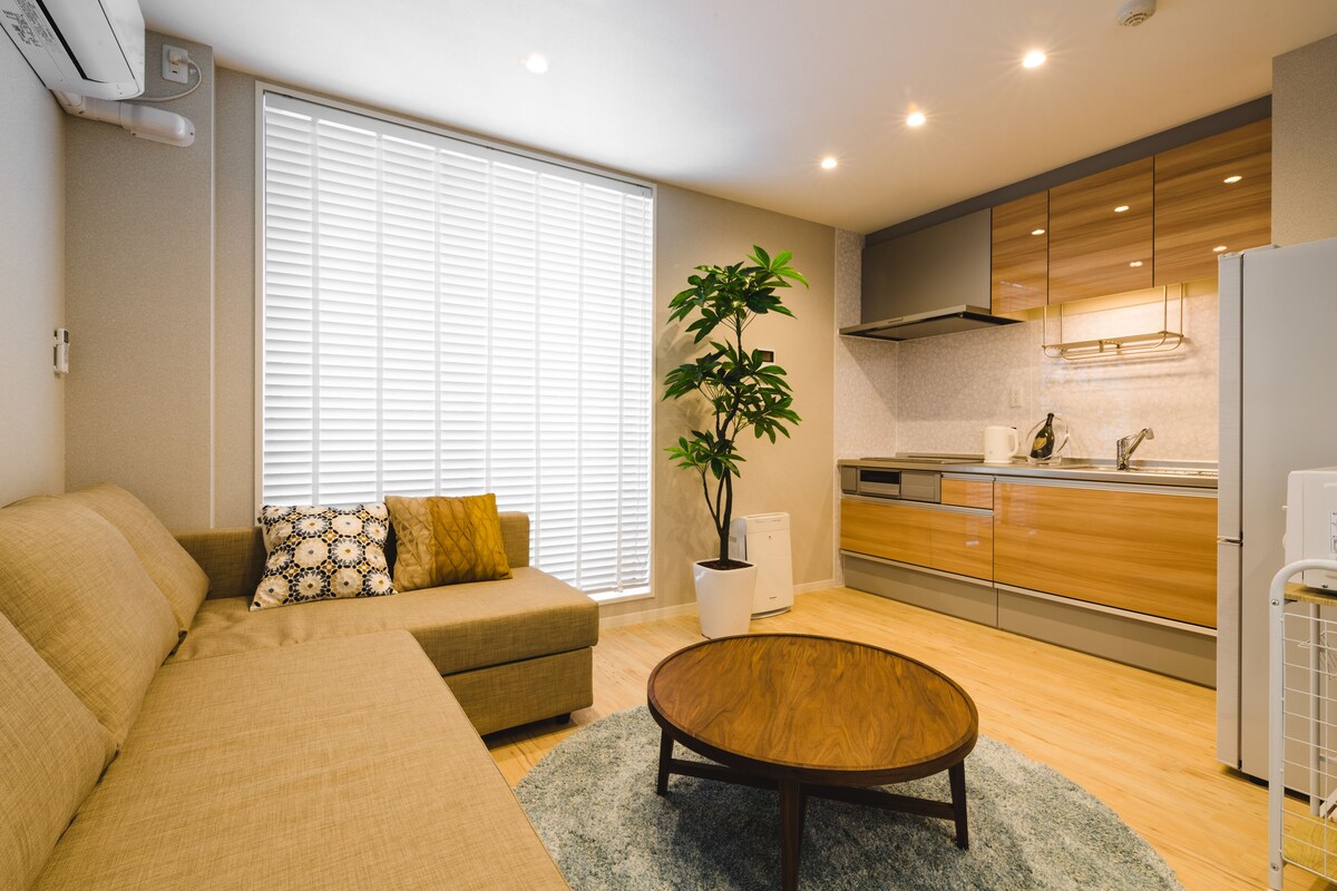 A modern living room with a sofa, a coffee table, and a potted plant.