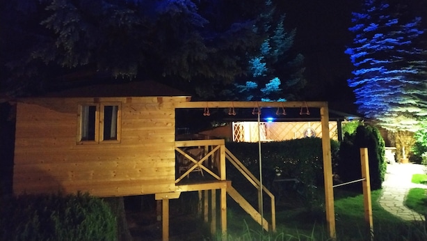 Une cabane en bois avec une petite fenêtre et un escalier menant à une terrasse.