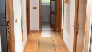 Un couloir avec des portes en bois, un tapis de couleur claire et des spots encastrés au plafond.