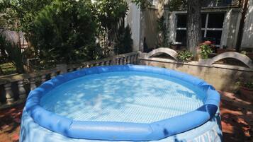 An inflatable pool surrounded by trees and a stone balustrade.