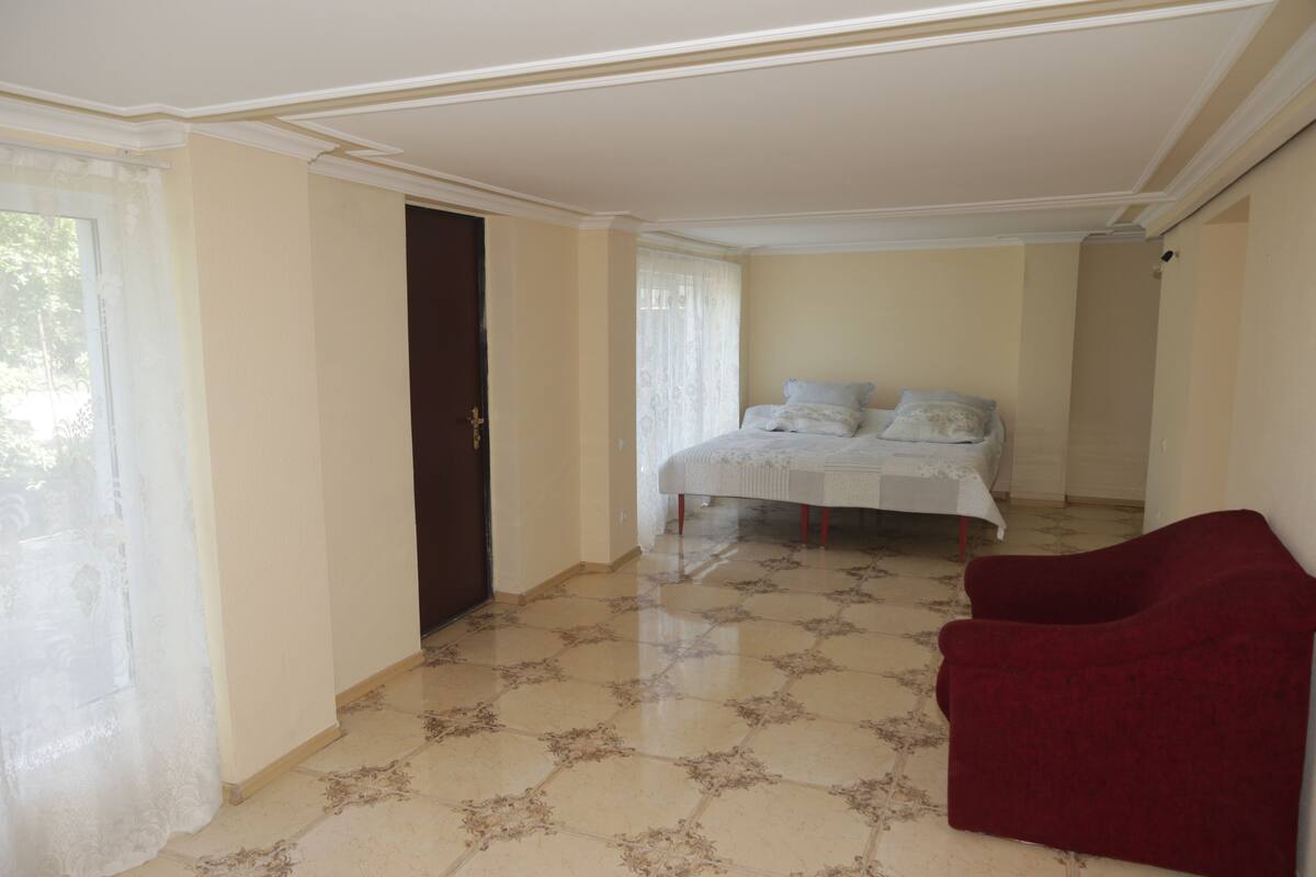 A bedroom with a bed, a red chair, and patterned flooring.