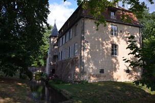 Un edificio histórico con fachada de piedra, múltiples ventanas y una torre destacada.