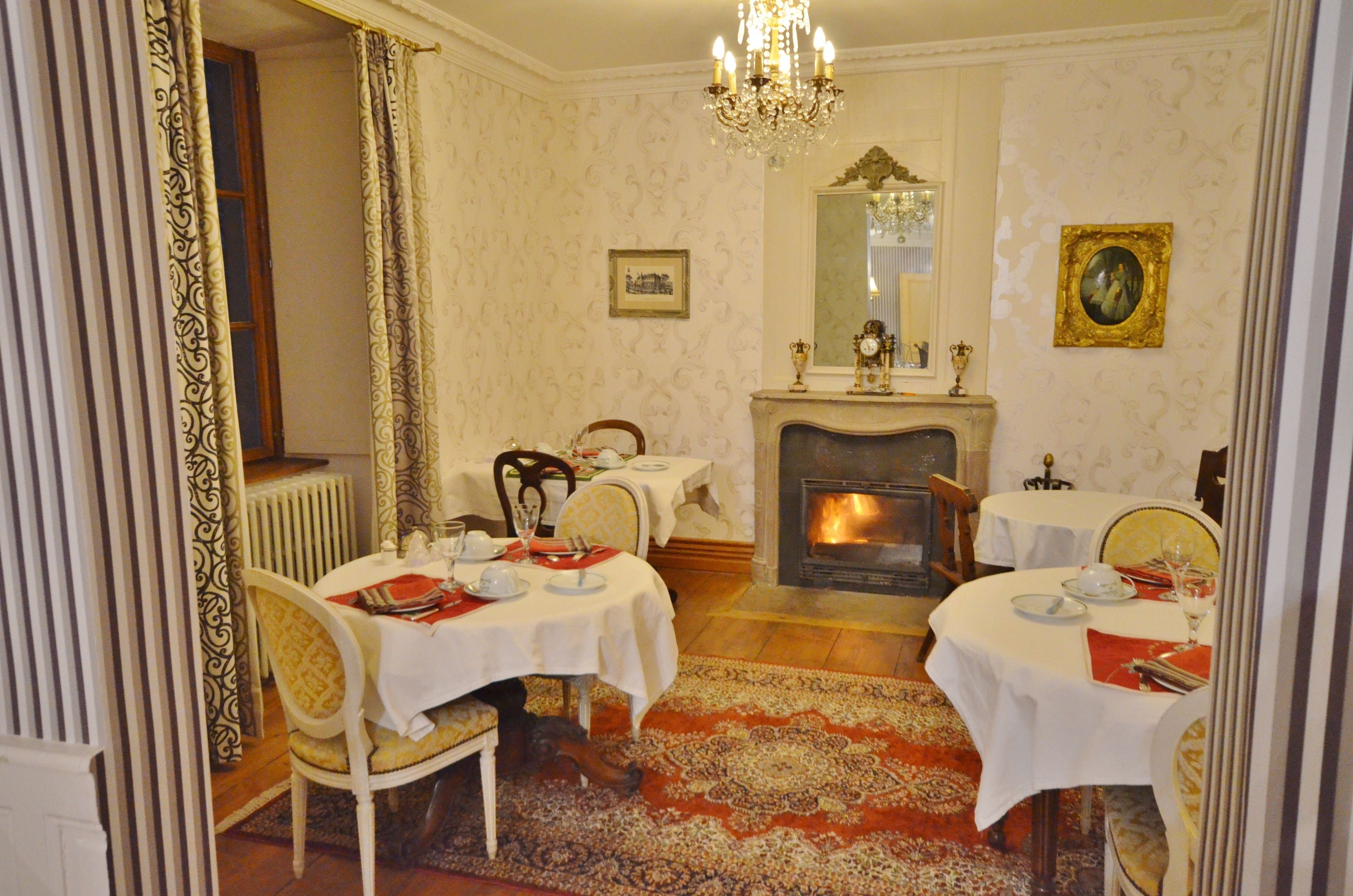 A dining room with two round tables set for dining, a fireplace, and a chandelier.
