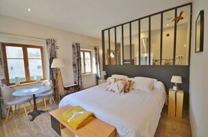 Una habitación de hotel con una cama, un escritorio, una silla, una mesa y un espejo grande.