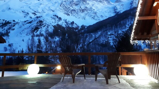 A wooden deck with two chairs and a table, overlooking a snow-covered mountain range. - Hotel Panoramic Village - La Grave (La Grave)