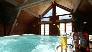An indoor swimming pool with wooden beams and large windows. - Hotel Panoramic Village - La Grave (La Grave)