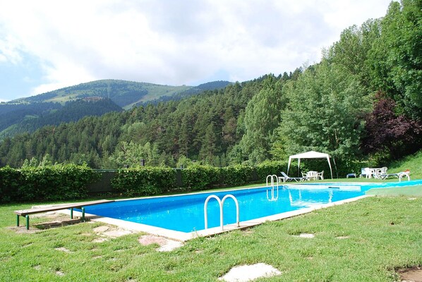 Ein Schwimmbecken mit Blick auf ein bewaldetes Gebirge.