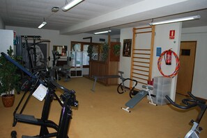 Ein Fitnessstudio mit verschiedenen Trainingsgeräten, darunter Laufbänder, Ergometer und Kraftgeräte.