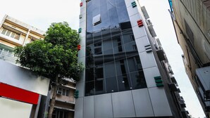 A modern building with a glass facade, multiple floors, and a tree in front. - OYO 15928 Hotel Midtown (Hyderabad)