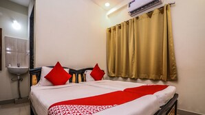 A hotel room with a bed, a bedside table, a sink, and a window with curtains. - OYO 15928 Hotel Midtown (Hyderabad)