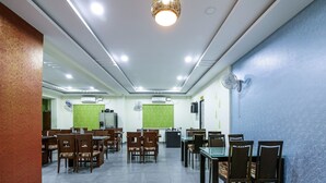A spacious dining area with multiple tables and chairs, air conditioning units, and a ceiling light fixture. - OYO 15928 Hotel Midtown (Hyderabad)