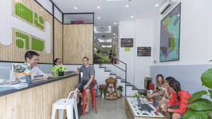 A reception area with a wooden counter, a reception desk, and a staircase leading to an upper level. - Hanoi Amazing Hostel (Hanoi)