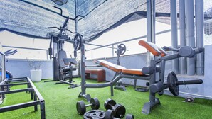 A gym with various exercise equipment, including dumbbells, a bench, and weight machines, on a green artificial turf floor. - Hanoi Amazing Hostel (Hanoi)
