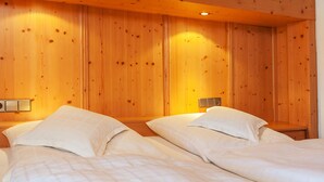 A room with two beds, wooden walls, and bedside lamps. - Haus Hubertus (Reit im Winkl)