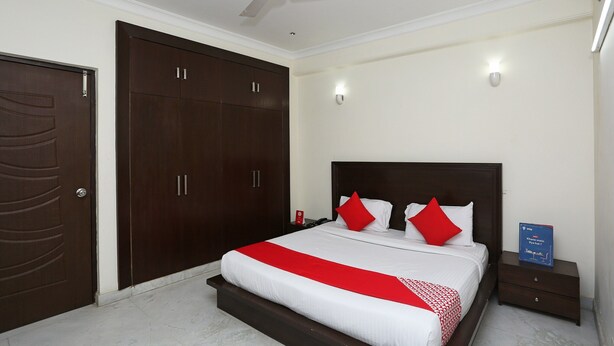 A bedroom with a bed, a wardrobe, a nightstand, and a ceiling fan. - OYO 15822 Ryan Residency (Gurugram)