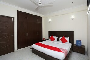 A bedroom with a bed, a wardrobe, a nightstand, and a ceiling fan. - OYO 15822 Ryan Residency (Gurugram)