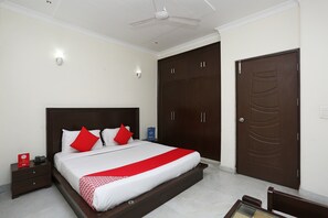 A neatly arranged bedroom with a large bed, a wardrobe, and a door. - OYO 15822 Ryan Residency (Gurugram)