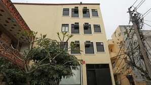 A multi-story building with a flat facade, multiple windows, and a large black gate at the bottom. - OYO 15822 Ryan Residency (Gurugram)