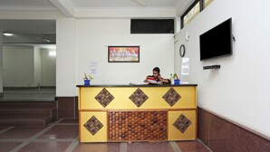 A reception desk with a patterned design, a clock, and a television on the wall. - OYO 15822 Ryan Residency (Gurugram)