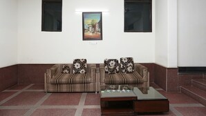 A room with a striped sofa set, a glass coffee table, and a framed painting on the wall. - OYO 15822 Ryan Residency (Gurugram)