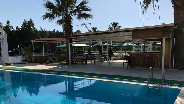 A swimming pool with a covered seating area, a bar, and a lifeguard stand. - New Iday Hotel (Kusadasi)