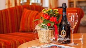 A bottle of wine, a glass, and a basket with flowers on a table. - Evis Wohnung (Reit im Winkl)
