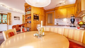 A kitchen with wooden cabinets, a dining table, and a built-in bench. - Evis Wohnung (Reit im Winkl)