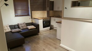 A compact kitchen with a built-in oven and a dining area with a dark-colored sofa. - Sub Penthouse Canary Wharf London (London)