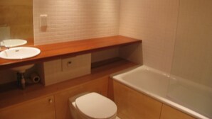 A bathroom with a wooden vanity, two sinks, a toilet, and a bathtub. - Sub Penthouse Canary Wharf London (London)