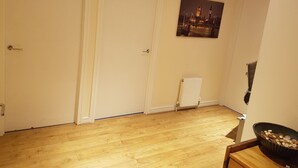 A room with wooden flooring, two white doors, a radiator, and a framed picture on the wall. - Sub Penthouse Canary Wharf London (London)