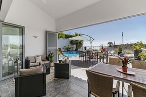 Un patio extérieur moderne doté d’une piscine, d’un espace salon et d’un coin repas.