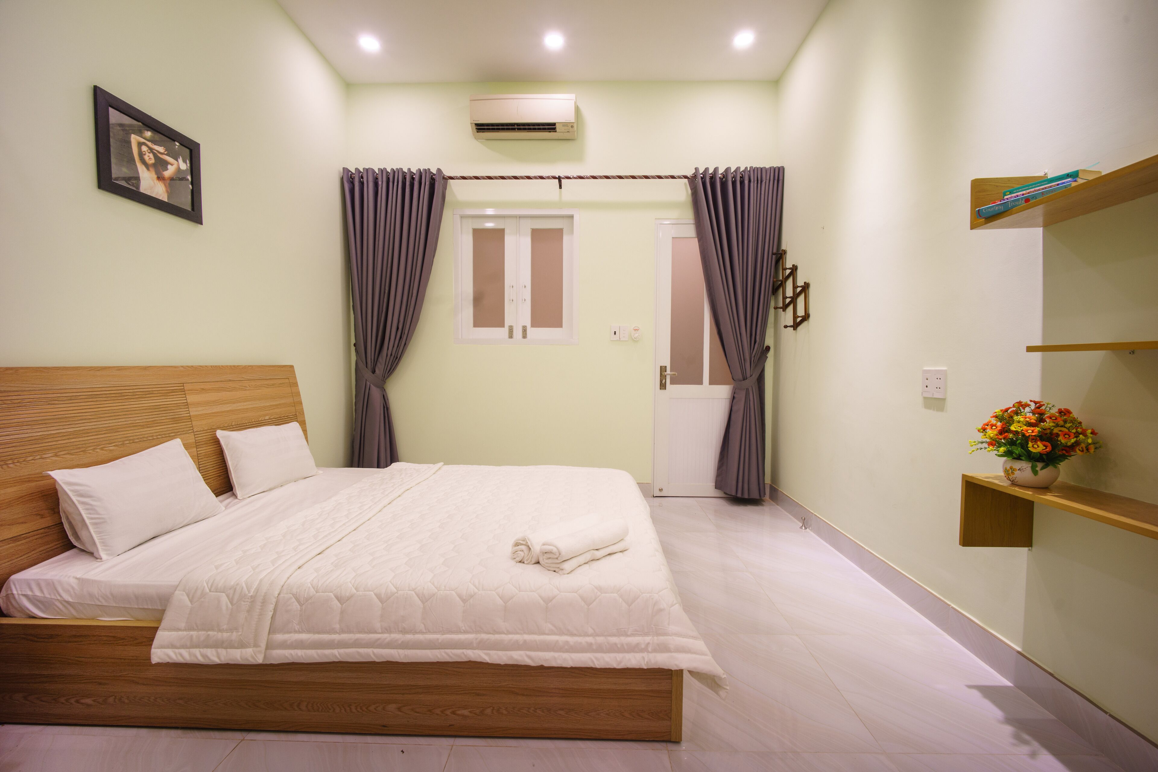 A bedroom with a wooden bed, a white mattress, and a beige wall.